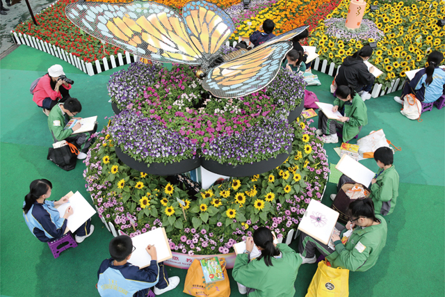 A rehabilitation butterfly made from recycled materials flutters at the Hong Kong Flower Show, and attracts many visitors to draw pictures of its movement.