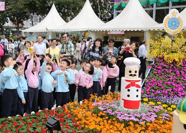 幼稚園學生參觀香港花卉展覽的懲教署攤位，不忘玩耍，充滿歡樂氣氛。