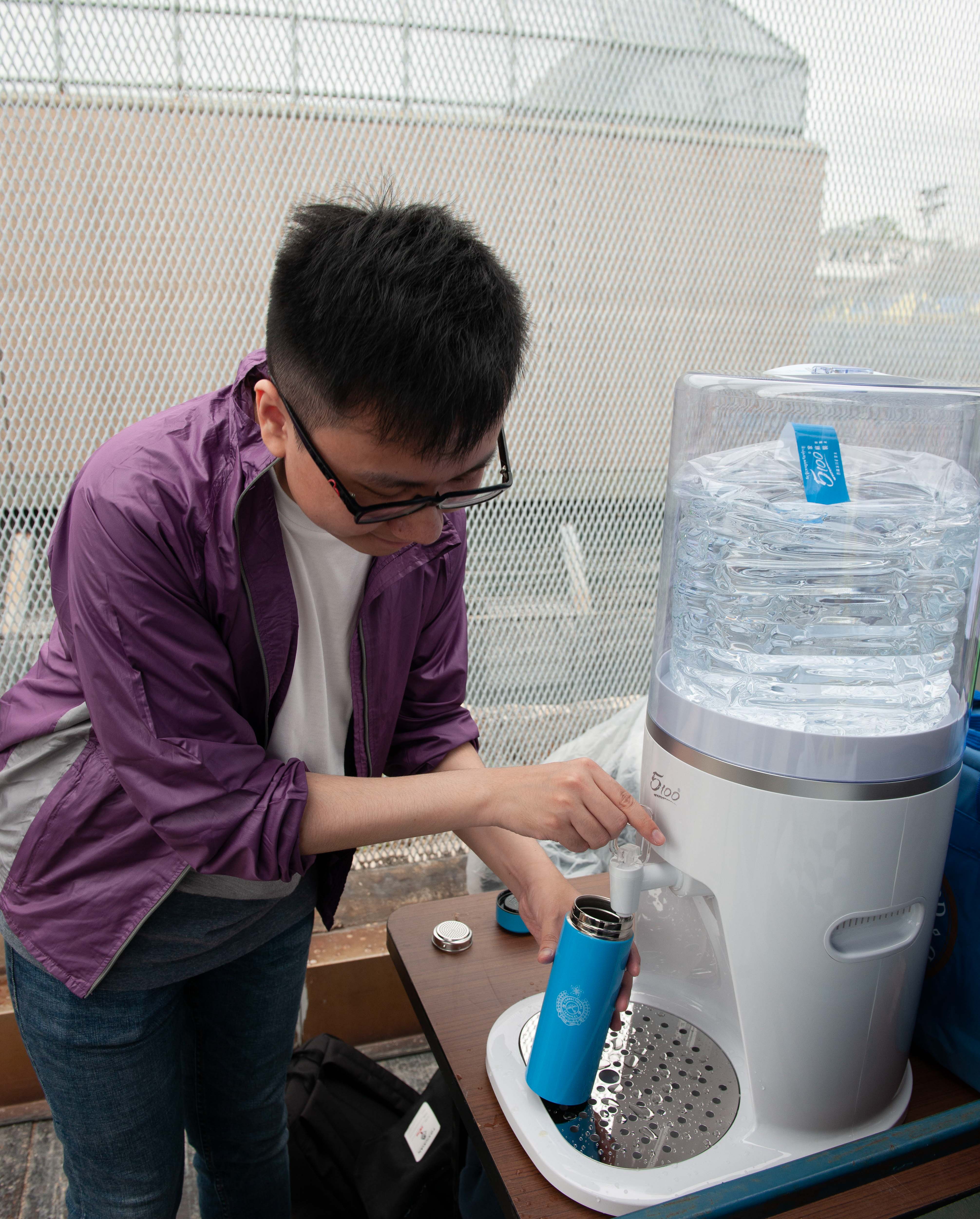 Staff refill their own bottles at water points.