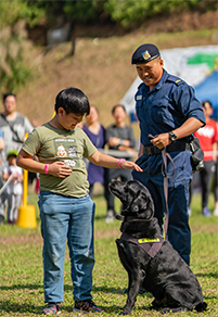 A correctional officer and a guard dog interact with participants at Family Outing on Hei Ling.