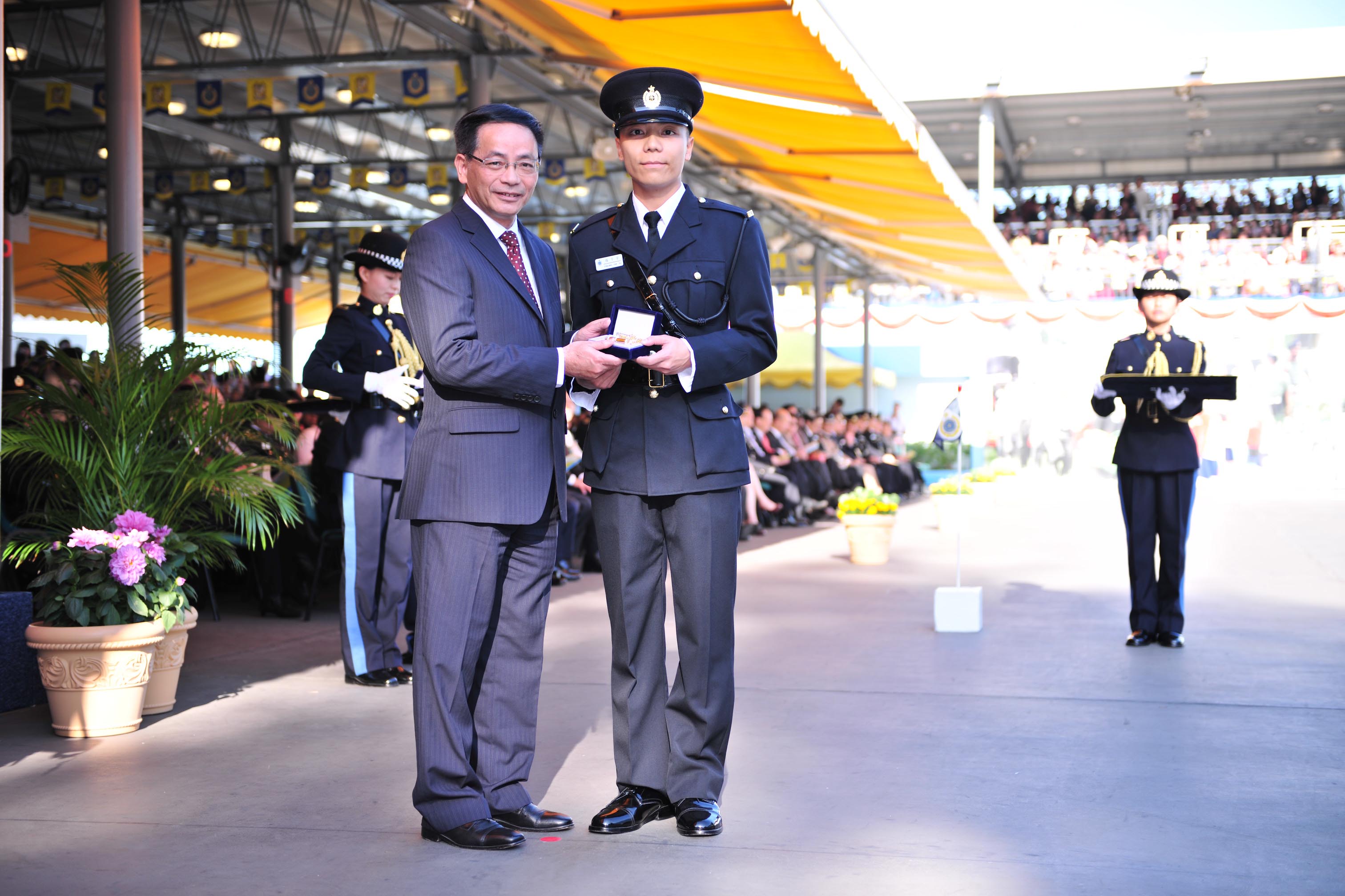 Mr Ip presents the Best Recruit Award, the Golden Whistle, to Assistant Officer II Cheung Chi-yu.