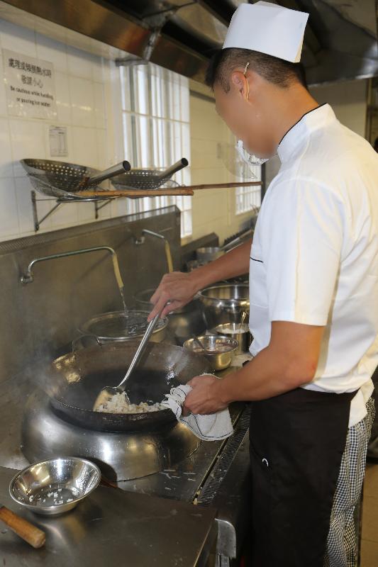 The Correctional Services Department held a vocational training course certificate presentation ceremony today (August 4) in Tong Fuk Correctional Institution. Photo shows a person in custody, who has completed the Chinese Cookery and Chinese Restaurant Service Certificate Course, demonstrates how to cook fried rice at the training kitchen.