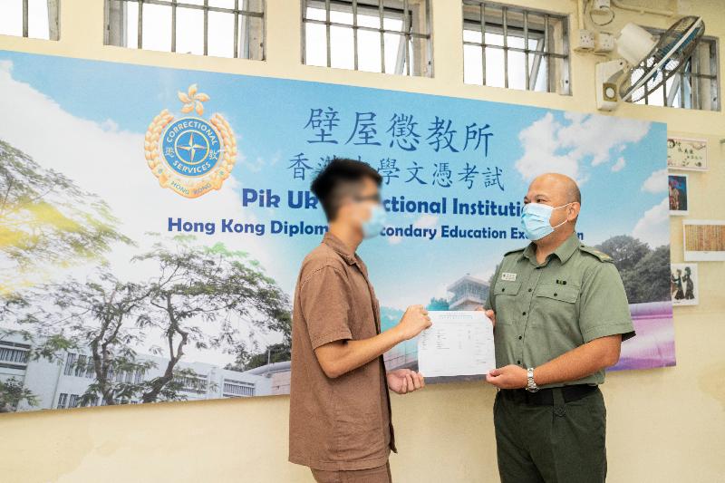今年共有七名青少年在囚人士報考香港中學文憑考試。圖示壁屋懲教所監督朱遠明（右）頒發香港中學文憑考試成績通知書予青少年在囚人士。