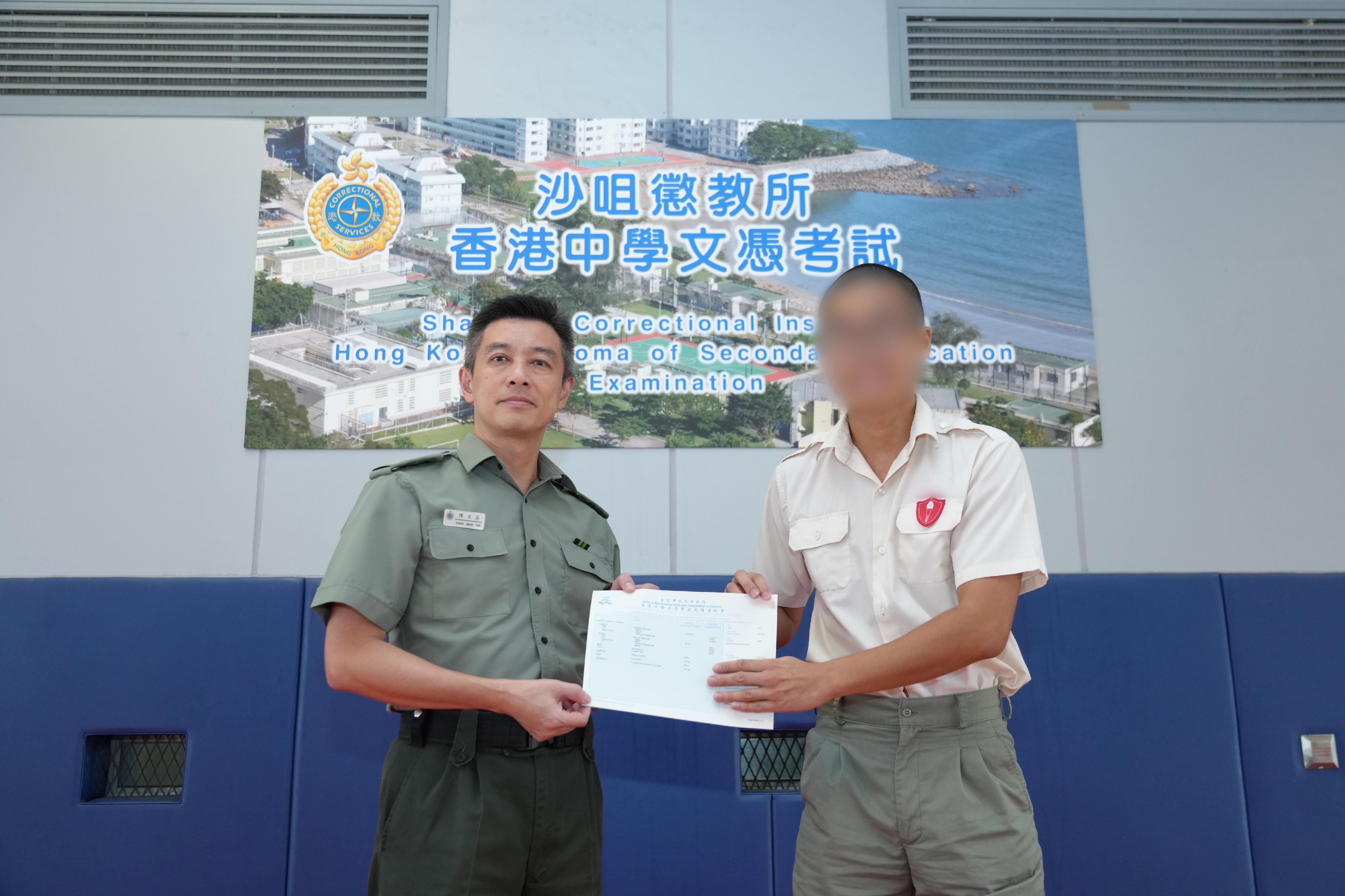 The results of the Hong Kong Diploma of Secondary Education (HKDSE) Examination were released today (July 19). Eighteen young persons in custody (PICs) enrolled in the HKDSE Examination this year. Photo shows the Superintendent of Sha Tsui Correctional Institution, Mr Chan Man-yat (left), presenting an examination certificate to a young PIC.