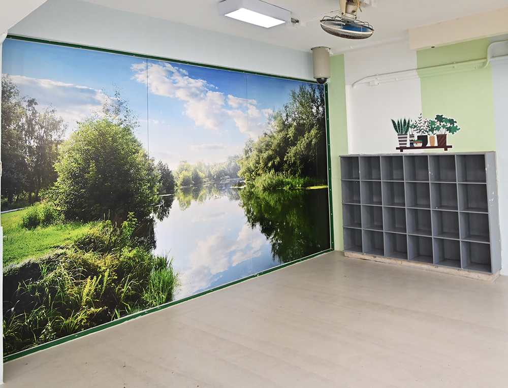 A dayroom for persons in custody with the application of environmental psychology in its design in which walls are painted sky blue and grass green, and a large picture of nature is displayed to alleviate the negative emotions of persons in custody and create a sense of hope for them.