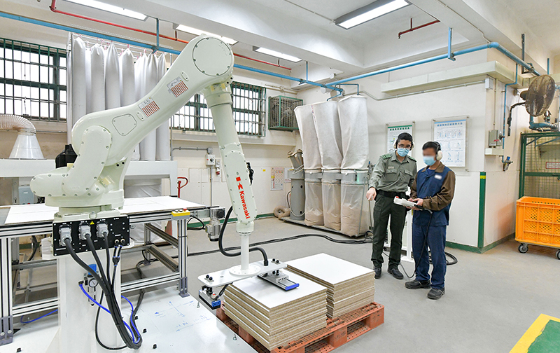 A person in custody learns how to use the automated production equipment in the Smart Carpentry Workshop of Pik Uk Prison.