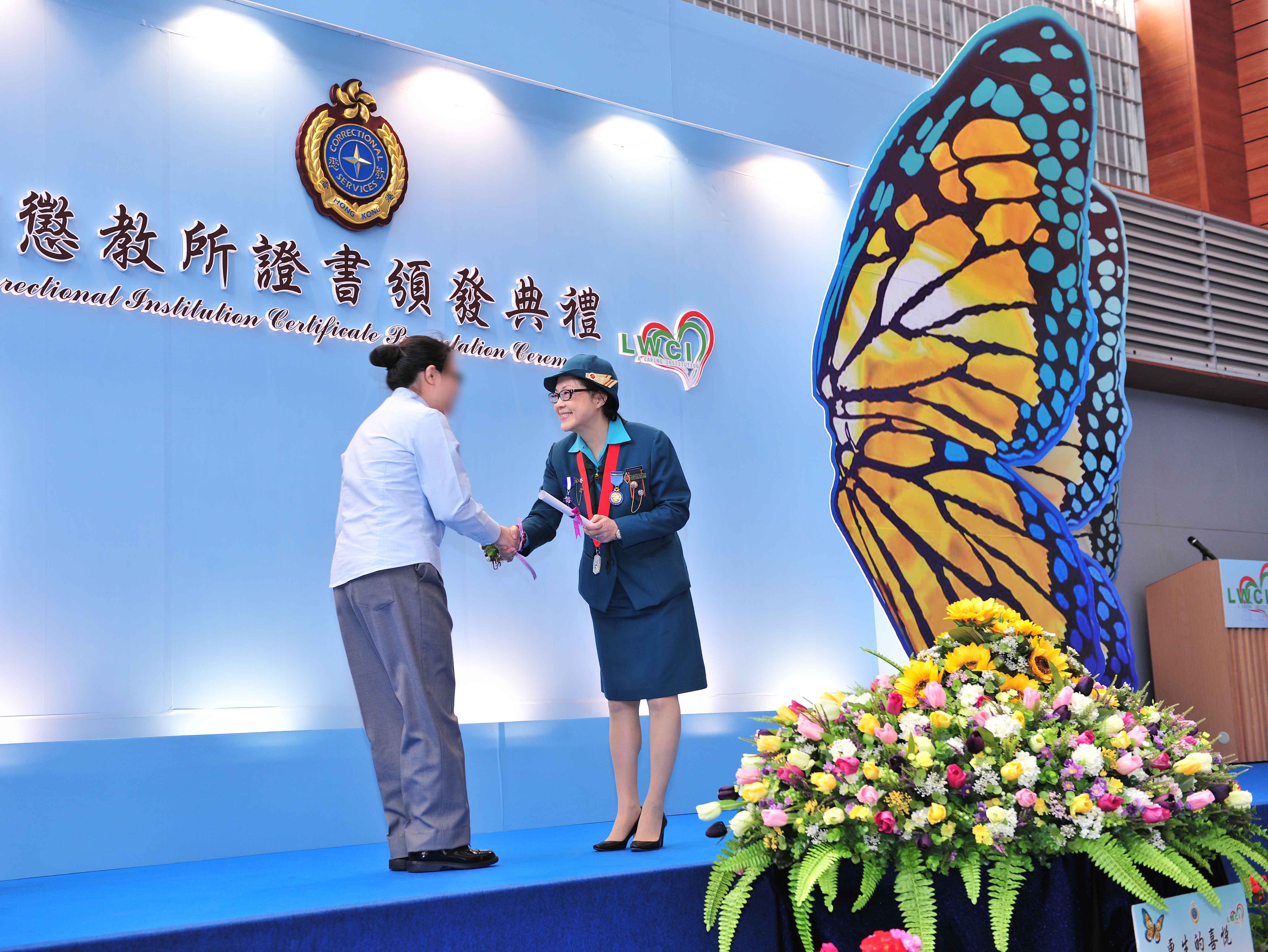 The Chief Commissioner of the Hong Kong Girl Guides Association, Mrs Josephine Pang, presents an academic certificate to an inmate representative at the presentation ceremony held in Lo Wu Correctional Institution today (March 6).