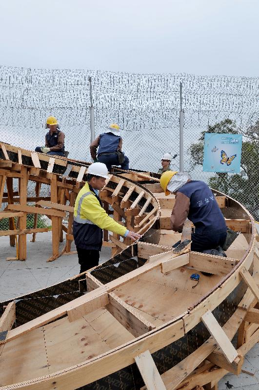 Persons in custody demonstrate the construction of a spiral staircase.