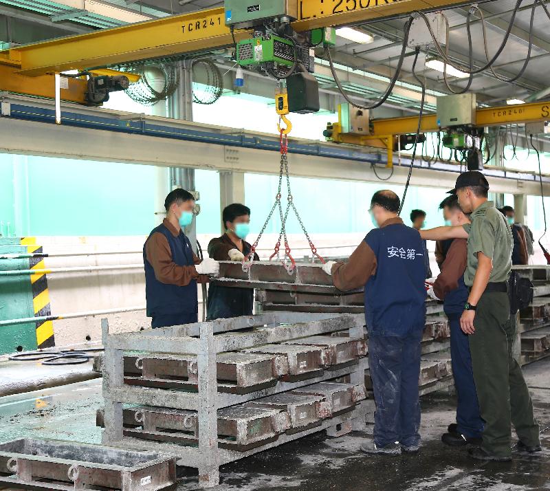 Persons in custody demonstrate the use of an overhead crane to lift concrete kerbs.