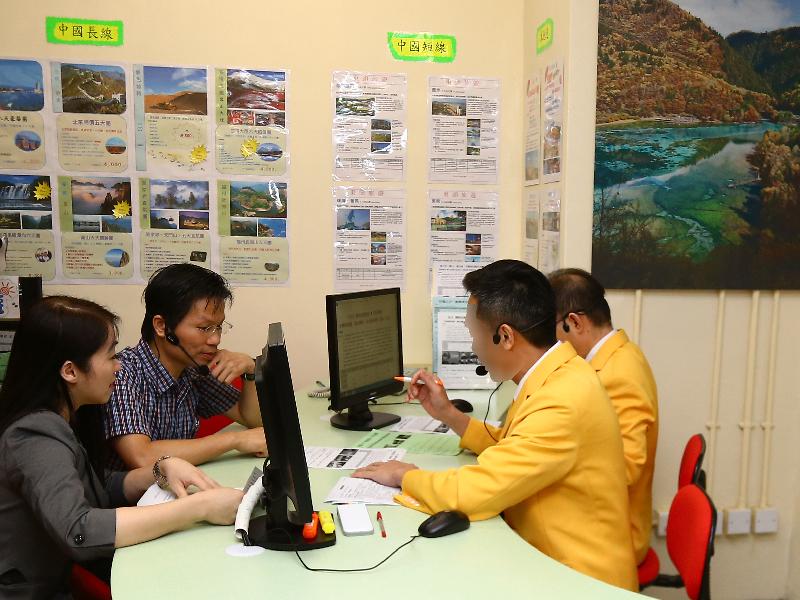 旅行社助理训练课程的毕业学员在模拟旅行社柜位，示范如何接待计划前往旅行的顾客。