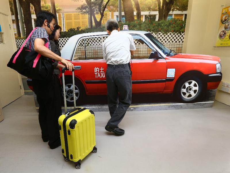 A graduate who participated in the Professional Taxi Driver (Taxi Written Test) training course demonstrates how to provide quality service at a mock taxi model.