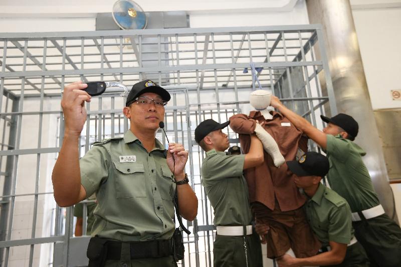 Correctional officers demonstrate how to save a person in custody attempting suicide by hanging at a cell.