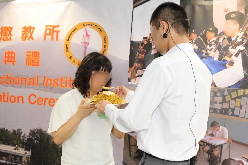 Thirty-four persons in custody at Cape Collinson Correctional Institution of the Correctional Services Department were presented with certificates at a ceremony today (September 6). Photo shows a person in custody (right) at the ceremony letting his mother (left) taste fried rice prepared by him.