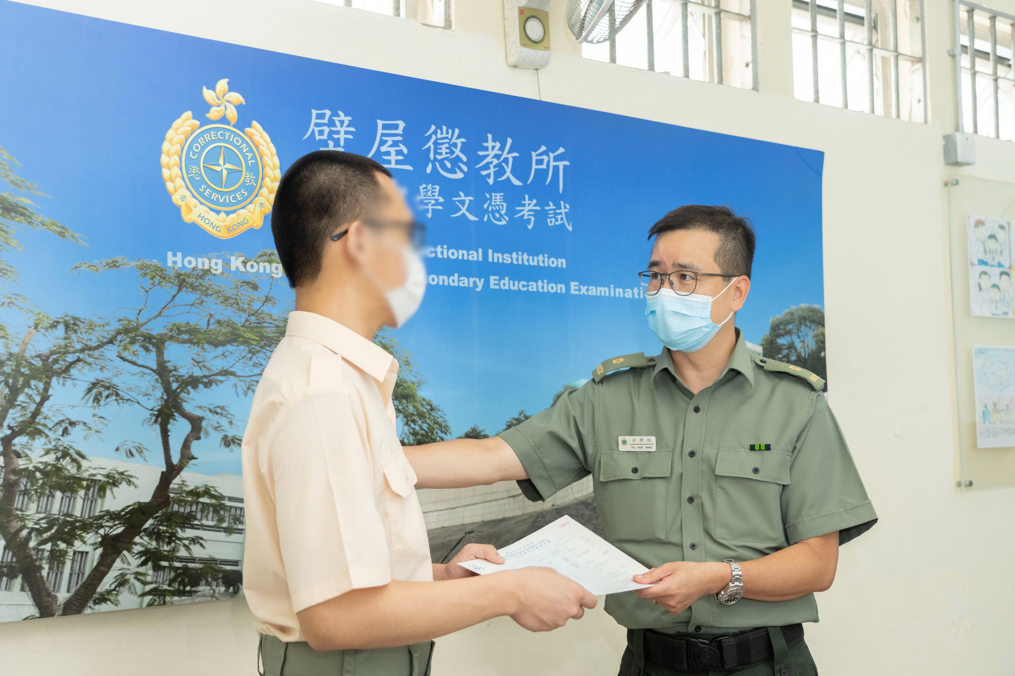 Twelve young persons in custody enrolled in the Hong Kong Diploma of Secondary Education Examination this year. Photo shows the Superintendent of Pik Uk Correctional Institution, Mr Yu Hok-ming (right), presenting an examination certificate to a young person in custody, Siu-kit (false name).