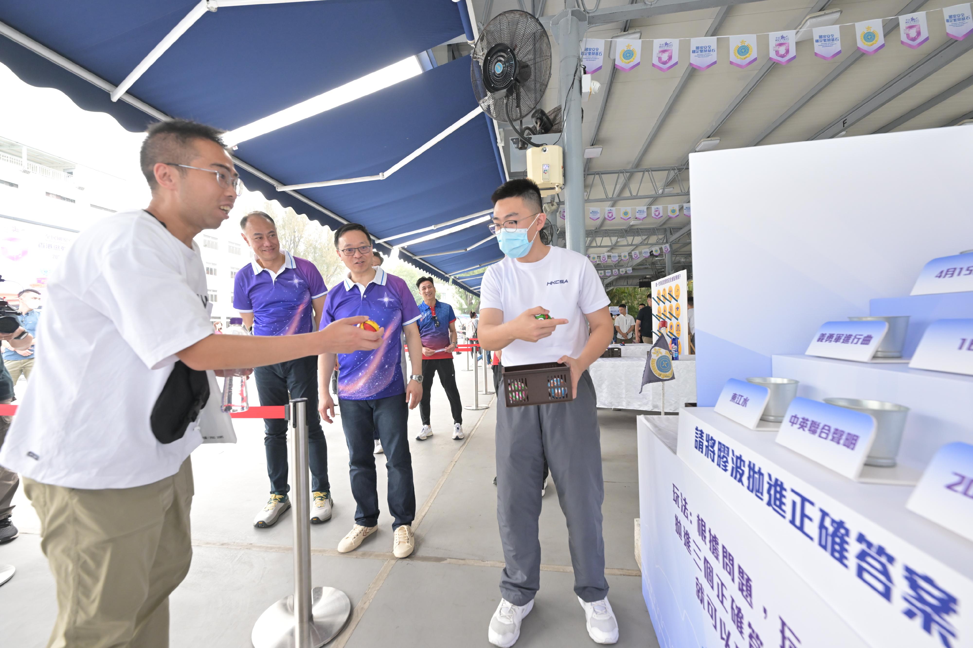 今日（四月十五日）是「全民國家安全教育日」，懲教署在香港懲教學院舉行開放日，加深市民對國家安全及懲教署工作的認識，包括維護國家安全領域的工作和成效。圖示懲教署署長黄國興（中）和副署長（更生及管理）梁建業博士（左二）觀看市民參與攤位遊戲。