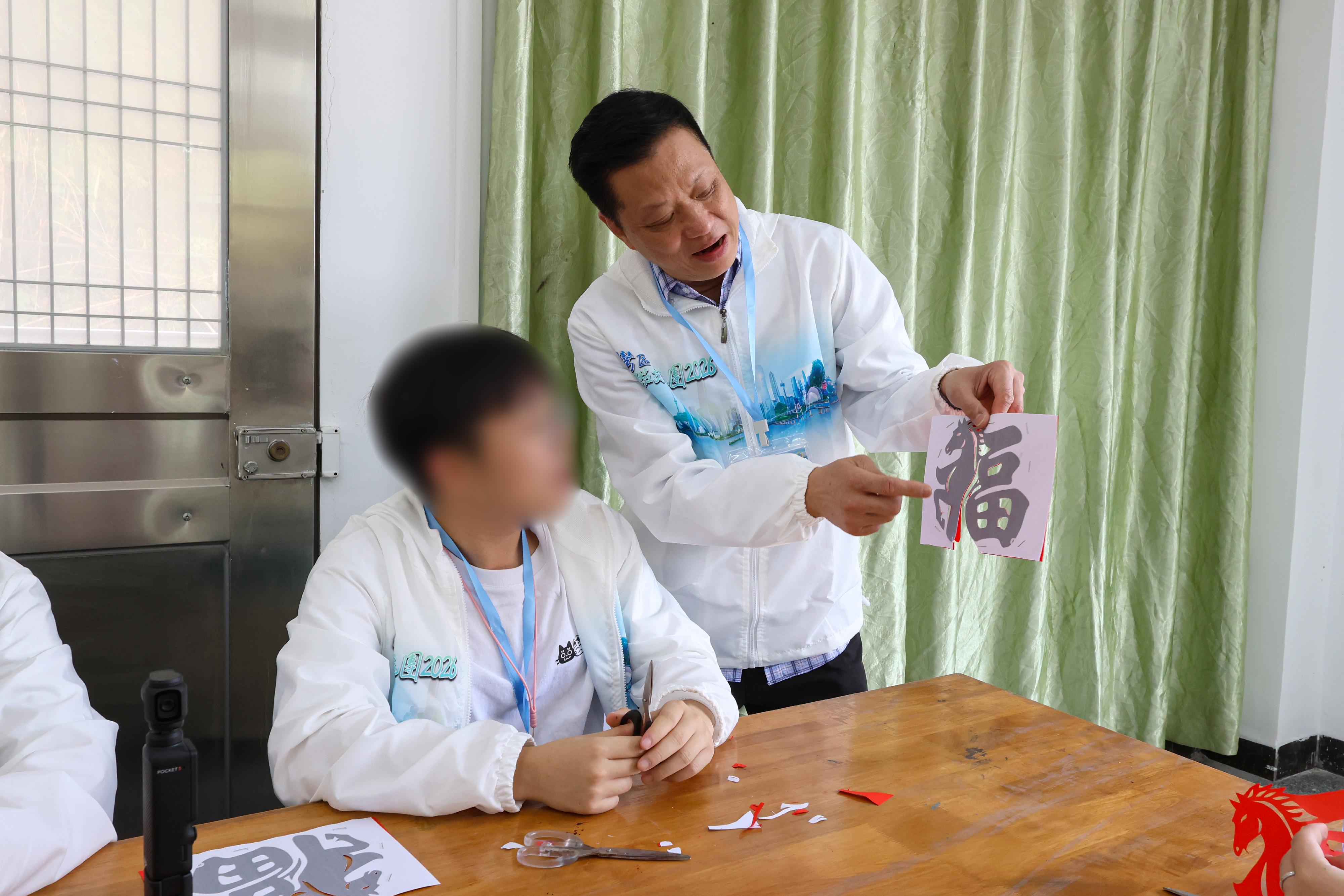 To further cultivate national consciousness and positive values in young rehabilitated persons, correctional officers led youths who have completed their sentences and are under statutory supervision to participate in the Greater Bay Area Experience Exchange Tour 2026, visiting Foshan and Zhuhai in the Guangdong-Hong Kong-Macao Greater Bay Area for three days and two nights of exchanges, so that they could learn about the country&rsquo;s history and culture as well as its developments in various fields. Photo shows the tour&rsquo;s sponsor, Mr Ha Chung-kin (right), leading a young rehabilitated person to experience the making of Chinese traditional handicraft at a school in Foshan on February 7, enabling him to understand the profound Chinese history and culture.