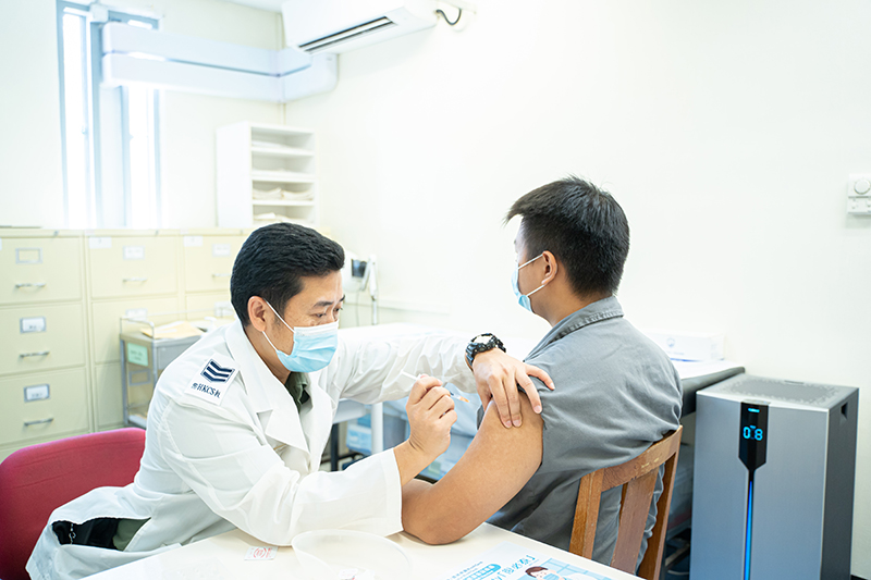 A correctional officer administers a COVID-19 vaccine to a person in custody.